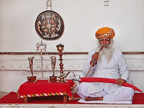An old Rajput man poses with a hookah in the Maharaja palace of Jodhpur.