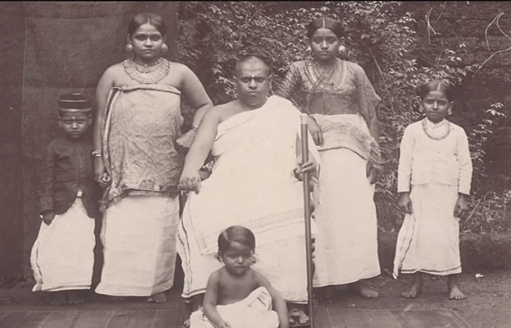 Historic black-and-white family photograph of members of the Thiyya community in Kerala. Several women, children, and an elder are posed together, reflecting the importance of the matrilineal Marumakkathayam family structure, where kinship, inheritance, and social identity were organized through the maternal lineage.