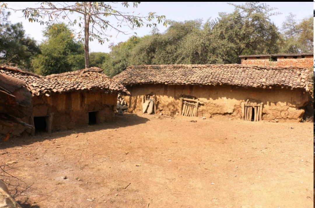 A traditional Munda village house with mud walls and a sloping clay-tiled khapra roof.